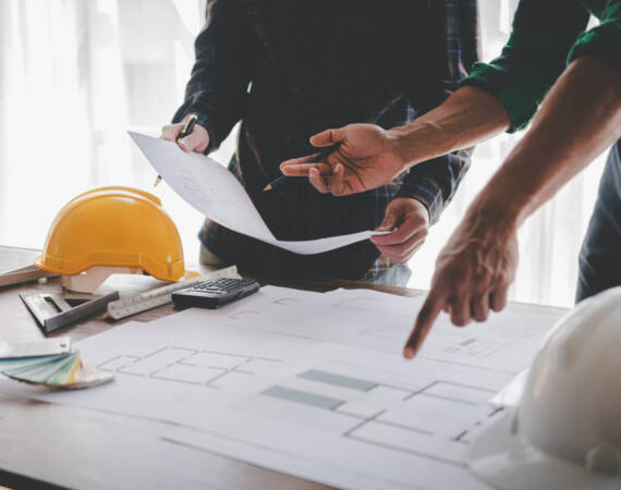 Engineers work as a team with blueprints for architectural plans